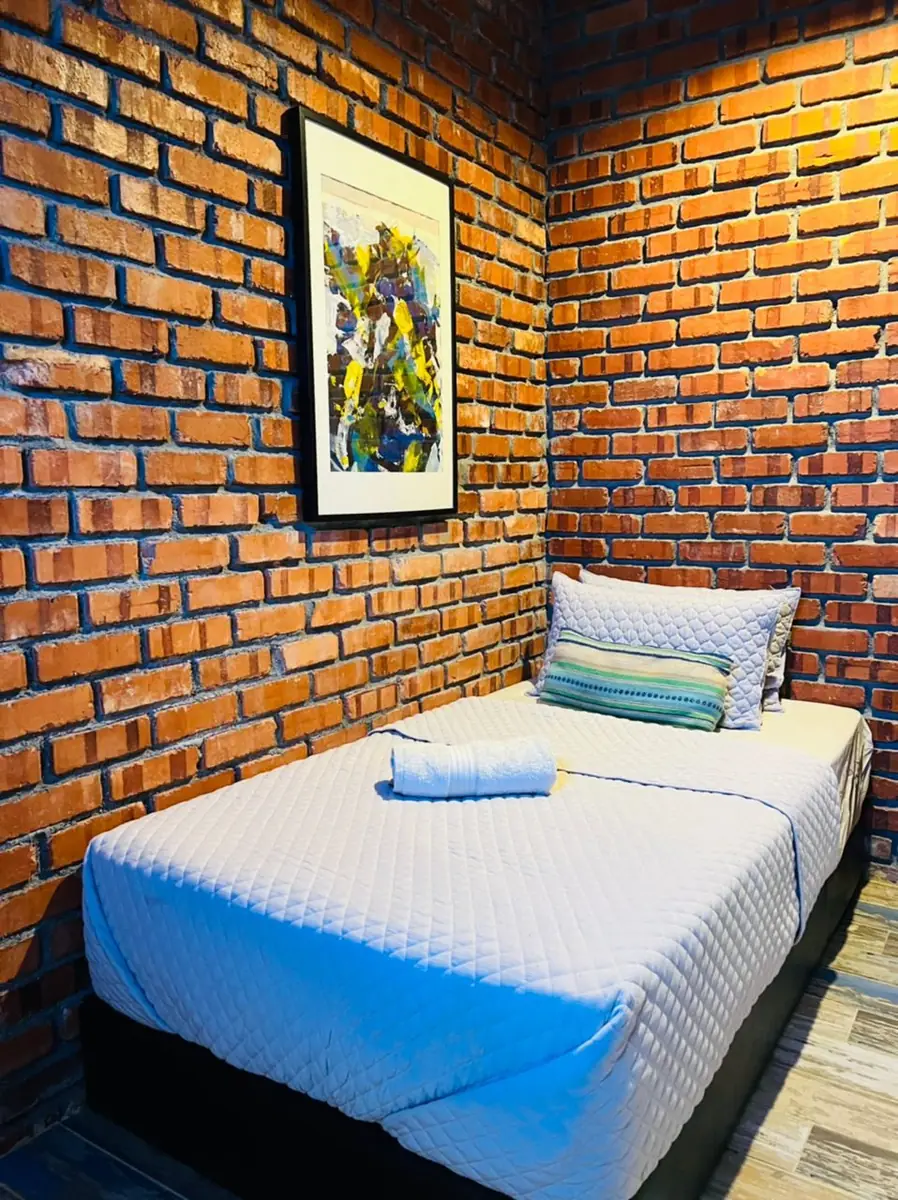 Single bedroom with brick walls and framed artwork