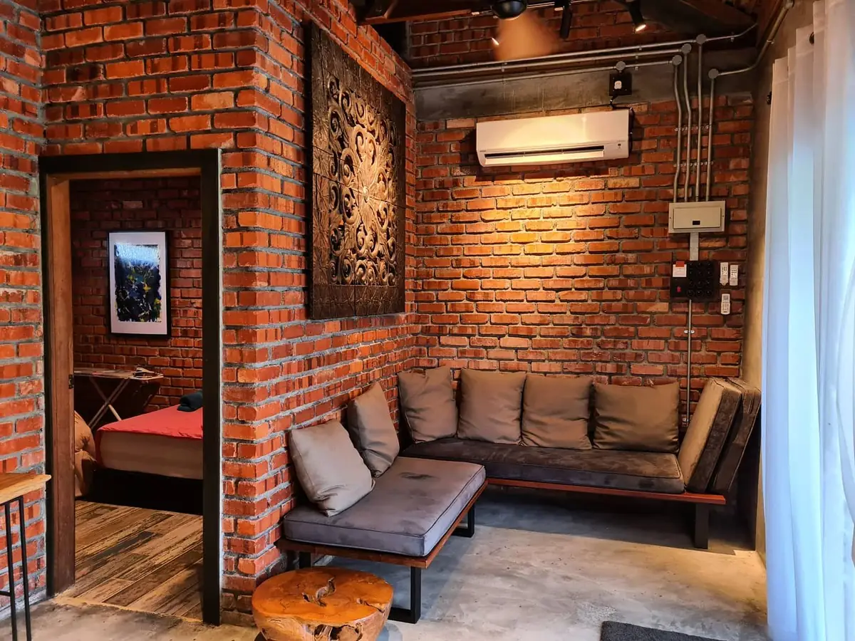 Corner sofa beneath a carved timber panel on the brick wall