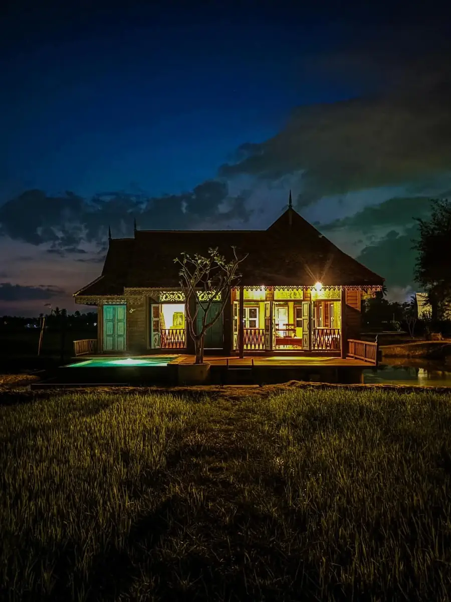 Rumah Uda glowing at night under a starry sky