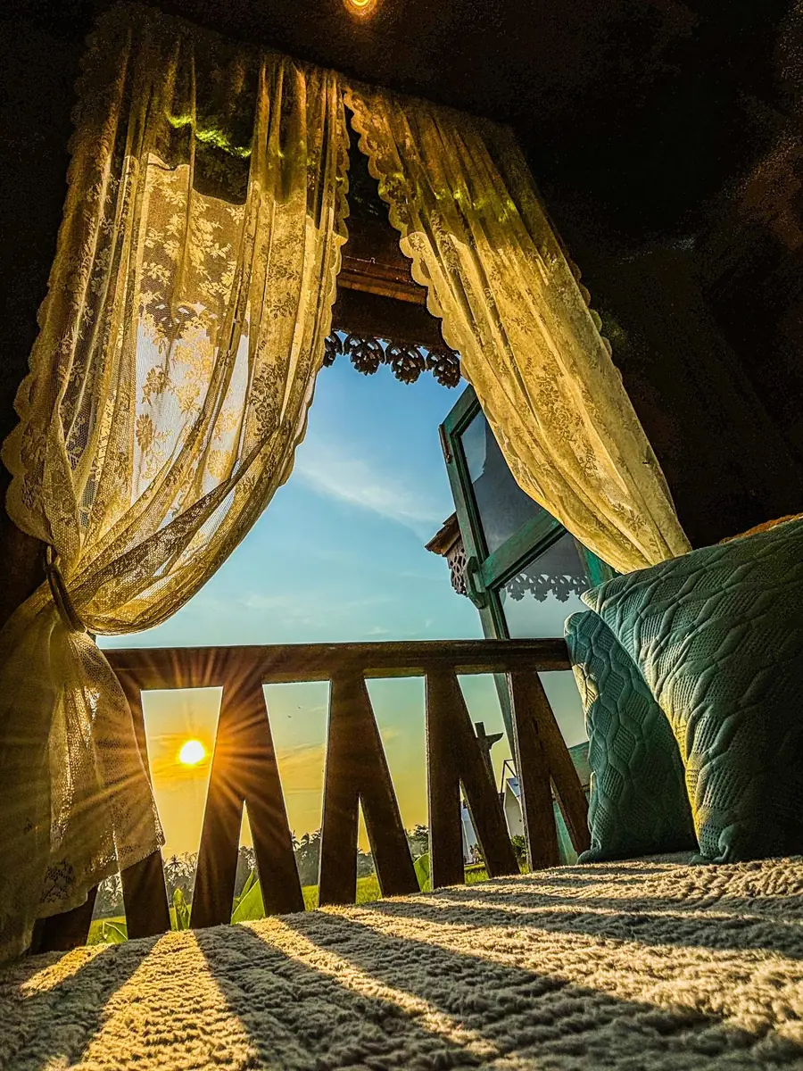 Sunrise over the padi fields seen from the bed through lace curtains