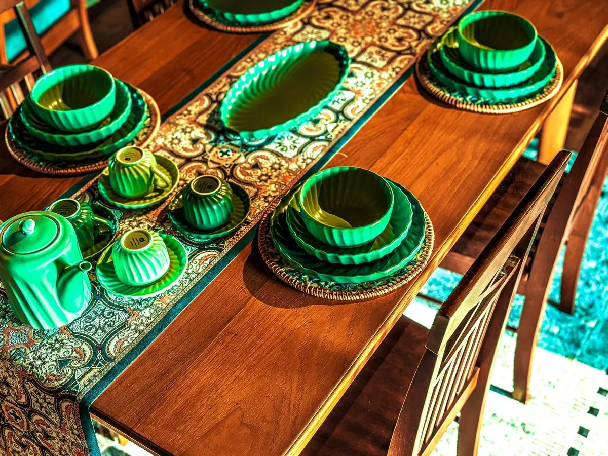 Green ceramic dining set laid out on the teak dining table
