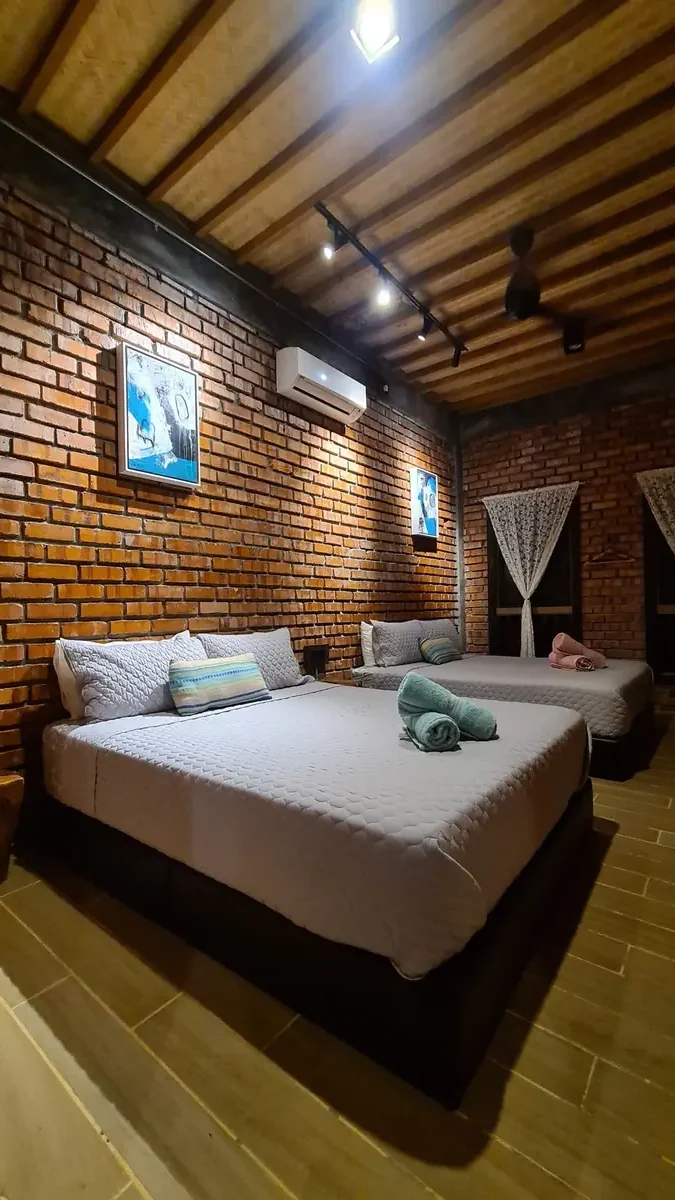 Downstairs bedroom with two queen beds against exposed brick